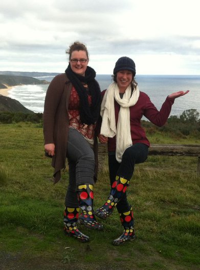 Two students showing their identical black gum boots with polka dots